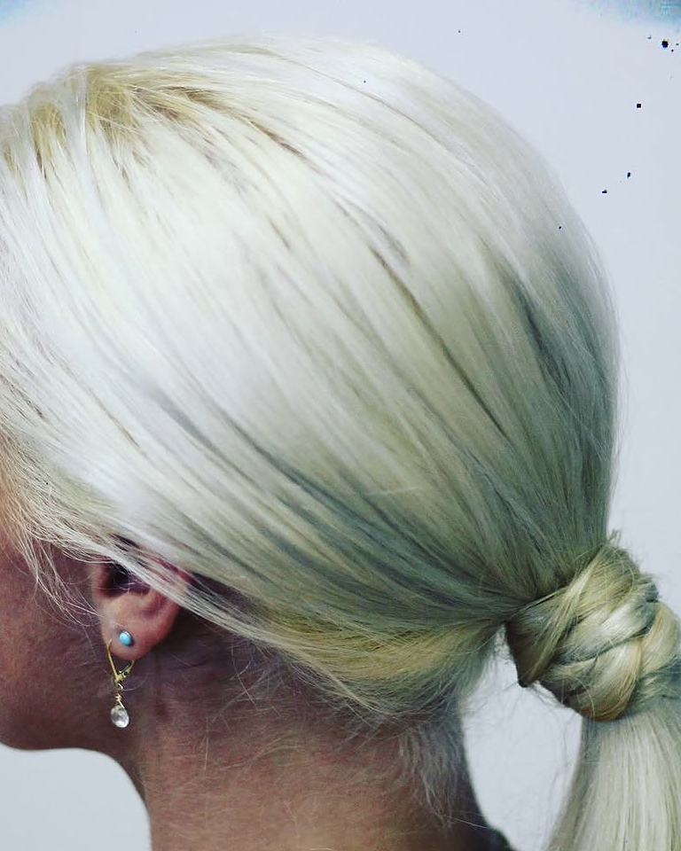 Sleek platinum low ponytail wrapped with its own hair