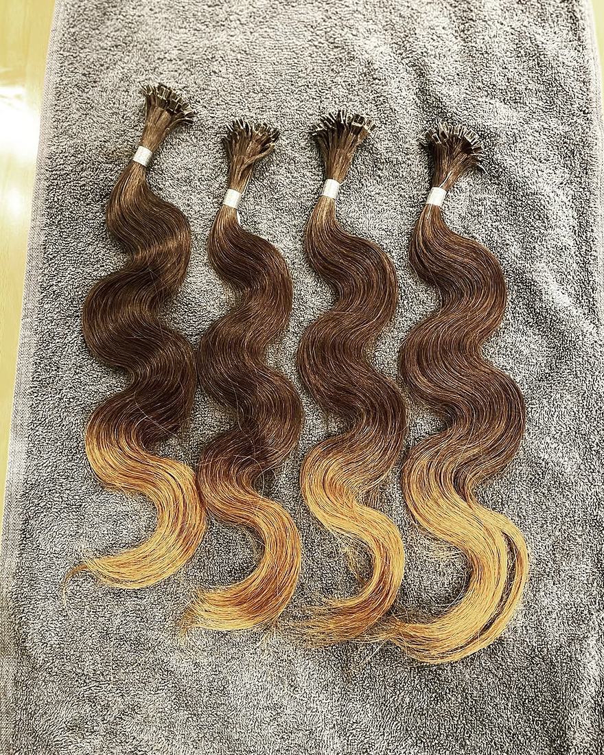 Four custom wavy keratin-tip strands blending from brunette to golden blonde