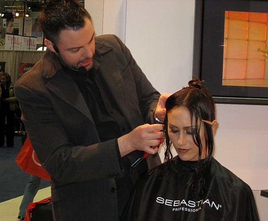 Christopher sectioning a model's wet hair at a Sebastian trade show booth