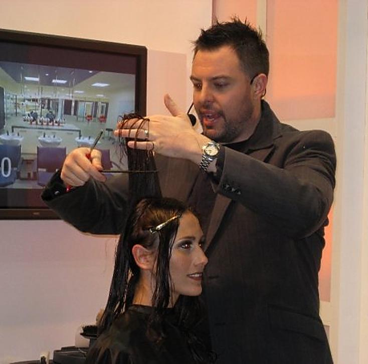 Christopher holding up sections of hair while explaining a cutting technique